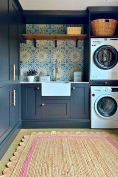 a washer and dryer in a laundry room with blue cabinets, rugs and baskets