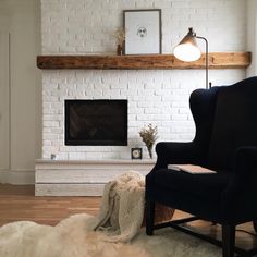 a living room with a white brick fireplace and black chair