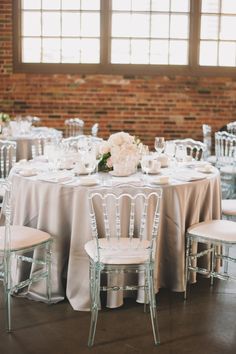 the tables are set with white linens and silver chairs for an elegant wedding reception