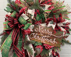 a christmas wreath with the words merry christmas written on it and green, red and white ribbons