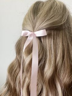 the back of a woman's head with long blonde hair and a pink ribbon