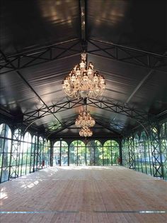 an empty room with chandeliers hanging from it's ceiling and glass walls