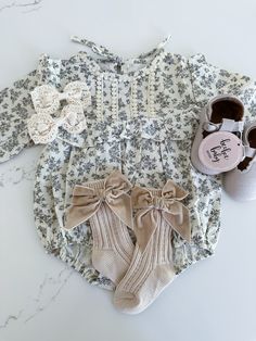 This long sleeve baby romper features a high neck and ruffled trim, perfect for keeping your little one stylish and comfortable. Made from soft cotton material, this romper also sports a beautiful floral print, adding a touch of charm and sophistication to any outfit. Cute Long Sleeve Onesie With Ruffles, Spring Long Sleeve Ruffled Onesie, Cute Long Sleeve Bubble Romper For Spring, Fitted Long Sleeve Onesie With Ruffles, Fitted Long-sleeved Onesie With Ruffles, Cute Long Sleeve Cream Bubble Romper, Cream Long Sleeve Bubble Romper For Summer, Cute White Jumpsuits And Rompers For Fall, Cute Long Sleeve Jumpsuits And Rompers For Fall