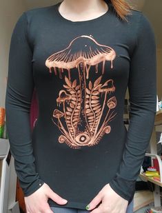 a woman wearing a long sleeved shirt with an image of a mushroom on it