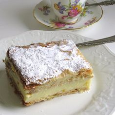 a piece of cake sitting on top of a white plate next to a cup and saucer