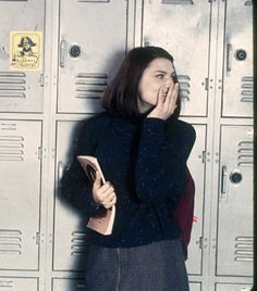 a woman standing in front of lockers talking on a cell phone