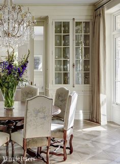 a dining room table with chairs and a chandelier hanging from the ceiling above it