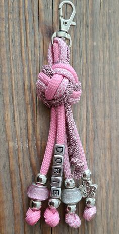 a pink keychain hanging on a wooden door with bells attached to the cord