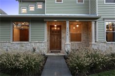 a house that has some lights on in front of it and bushes outside the door