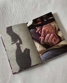 an open book with the shadow of a man's hand on it