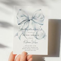 a person holding up a white card with a bow on the front and bottom, which reads something blue happens to be a bridal shower