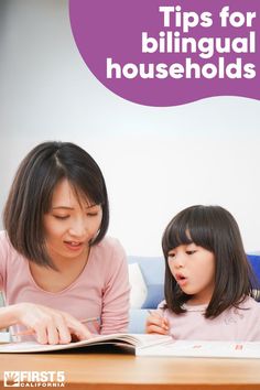 an adult and child are sitting at a table with a book in front of them