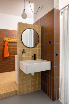 a bathroom with a sink, mirror and shower stall in the corner next to tiled walls