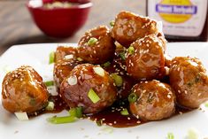 a white plate topped with meatballs covered in gravy and sesame seed seeds