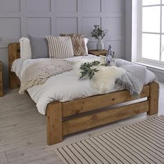 a bed with pillows and blankets on top of it in a room next to a window