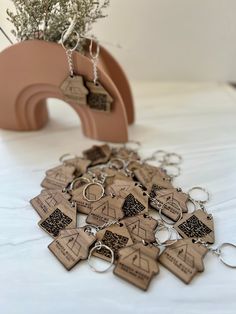 a bunch of wooden keychains sitting on top of a white table next to a potted plant