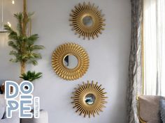 three mirrors are hanging on the wall above a couch in a room with white walls