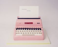 an old fashioned pink typewriter sitting on top of a white table next to a piece of paper