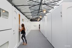 a woman is standing in the hallway between two white lockers with doors on each side