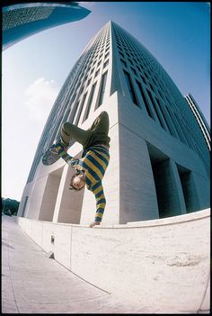 a skateboarder doing a trick in front of a tall building