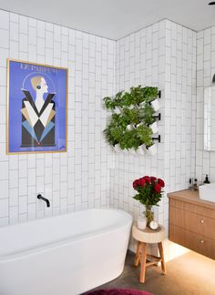 a white bath tub sitting next to a bathroom sink under a painting on the wall