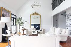 a living room with white furniture and pictures on the wall