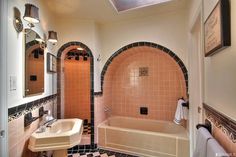 a bathroom with black and white checkered flooring, pink tile walls and bathtub