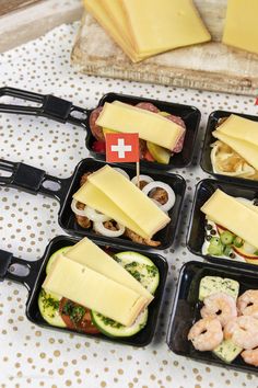 several trays filled with different types of food on top of a white tablecloth