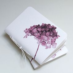 three notebooks with purple flowers on them sitting next to each other and tied together