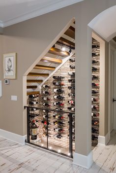 a wine cellar under a stair case in a room with beige walls and flooring