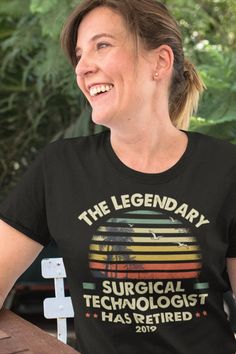 a woman sitting at a table smiling and wearing a shirt that says the legendary surgical technology has retired