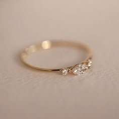 a gold ring with three diamonds on it sitting on a white tableclothed surface