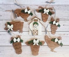 wooden cutouts of farm animals hanging from clothes pins on a white wood background with green leaves and bows