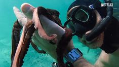 a man wearing a diving mask and holding an octopus in his hand while swimming underwater