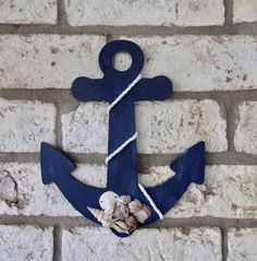 an anchor and seashells hang on a brick wall with a rope around it