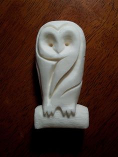 a white owl figurine sitting on top of a wooden table