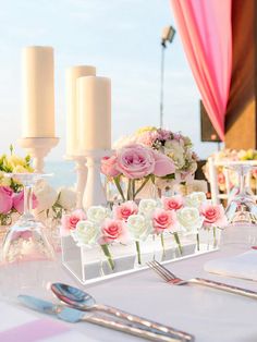 the table is set with flowers and candles for an elegant wedding reception at the beach