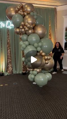 a woman standing in front of a large balloon arch with gold and silver balloons on it