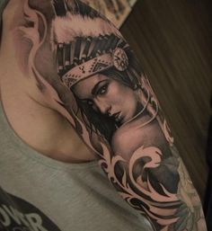 a man with a tattoo on his arm and headdress is posing for the camera