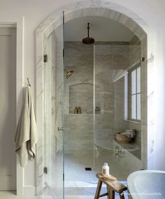 a bathroom with a walk in shower next to a white bath tub and wooden stool