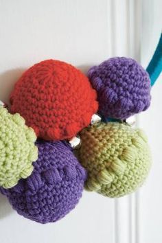 crocheted balls hang from a hook on a door