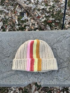 a knitted hat sitting on top of a stone bench next to leaves and grass