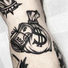 a man's arm with tattoos on it, including money bags and other symbols