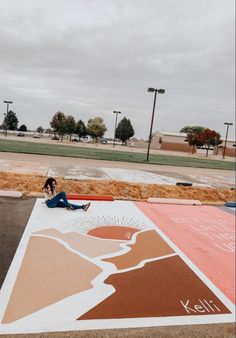 a person sitting on the ground next to a painting