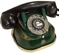 an old fashioned green phone is sitting on a white surface with black and gold trim