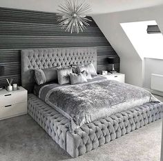 a large bed sitting in the middle of a bedroom under a chandelier above it