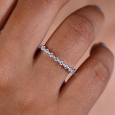 a woman's hand with a diamond ring on it, showing the band and side stones