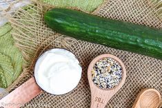 two wooden spoons with yogurt and cucumbers on them next to each other