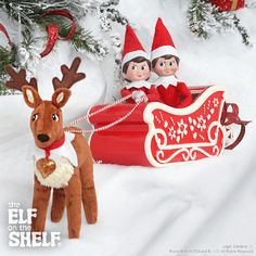 two elfs are riding in a sleigh with a reindeer on the side