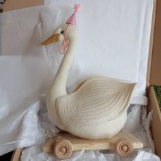 a white swan with a pink hat on it's head sitting in a box